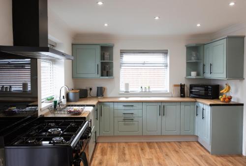 a kitchen with green cabinets and a stove top oven at Large 4 Bed Home - Fast Wifi, Smart TV's & Free Parking - Near A66 in Stockton-on-Tees