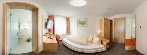 a bedroom with a large white bed and a bathroom at Landhotel Steigenhaus in Untermünkheim