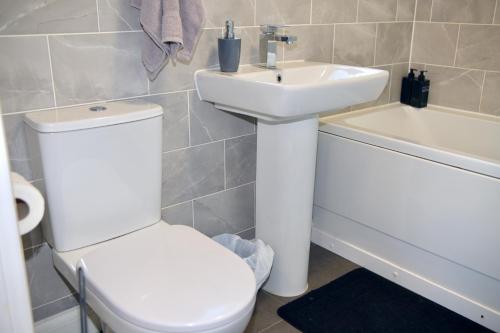 a bathroom with a toilet and a sink and a tub at Modern house in City Centre with private parking and gated property in Birmingham