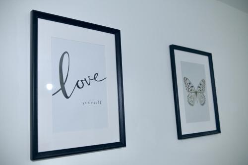two picture frames with a butterfly on a wall at Modern house in City Centre with private parking and gated property in Birmingham
