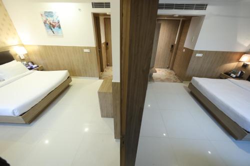 two beds in a hotel room with white floors at Hotel Elevate Suites Near Delhi Airport WITH- Free Airport PICKUP in New Delhi