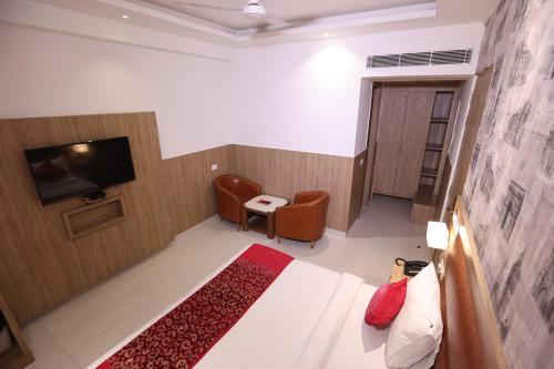 a hotel room with a bed and a chair and a television at Hotel Elevate Suites Near Delhi Airport WITH- Free Airport PICKUP in New Delhi