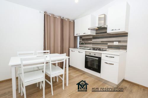 a kitchen with white cabinets and a table and chairs at Le Querce Appartamento Roma in Infernetto