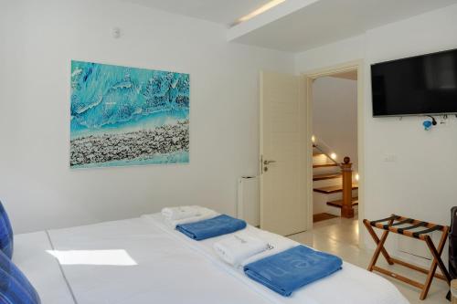 a white room with a bed with two towels on it at Blueros - Olive suite in Megas Yialos-Nites