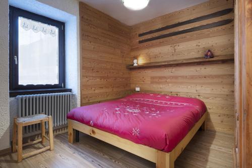 ein Schlafzimmer mit einem roten Bett in einer Holzwand in der Unterkunft Chalet Diamond - AffittiPontediLegno in Ponte di Legno