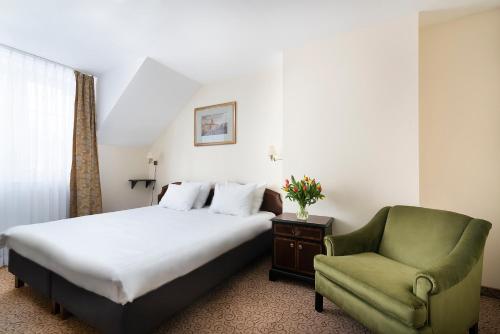 a hotel room with a bed and a green chair at Hotel Wisła Premium in Wisła