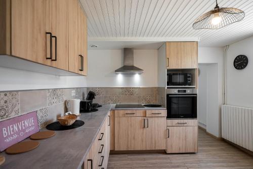 une cuisine avec des armoires en bois et un four à plaques de cuisson dans l'établissement Maison Amélia, à Parentis-en-Born