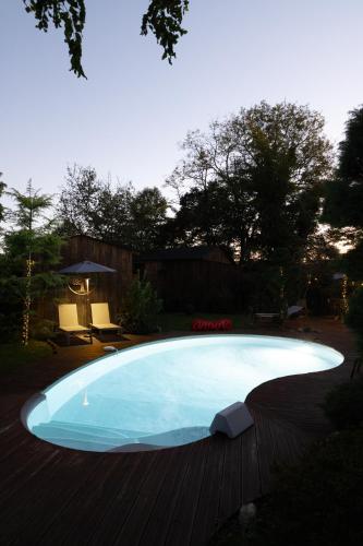 une grande piscine bleue sur une terrasse en bois dans l'établissement Coup de coeur villa, agglo Pau (15 min), à Mirepeix