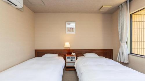 two twin beds in a room with a window at 琴弾荘 in Kanonji