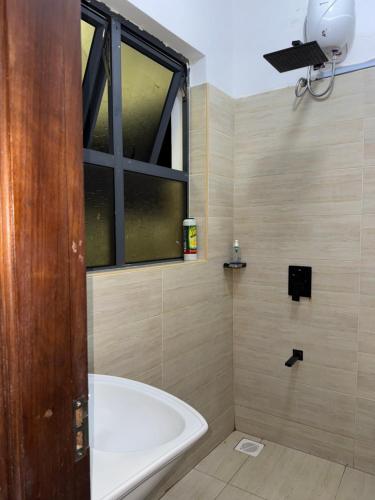 a bathroom with a bath tub and a window at Kheyre Nyali Ocean View Studio Apartments in Mombasa