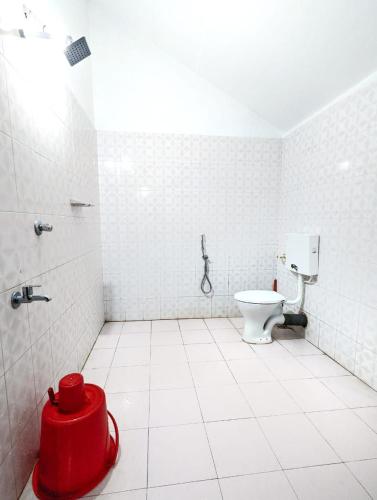 a bathroom with a toilet and a red bucket at Wintervilla Cottages in Meppādi