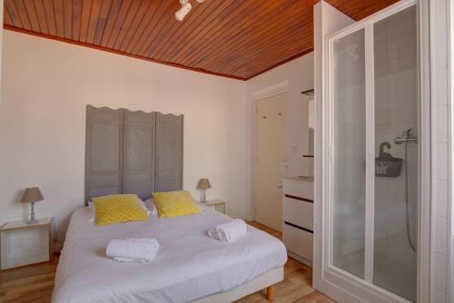 une chambre avec un lit blanc avec des oreillers jaunes dans l'établissement Maisonnette de l'Aiguillon, à Arcachon