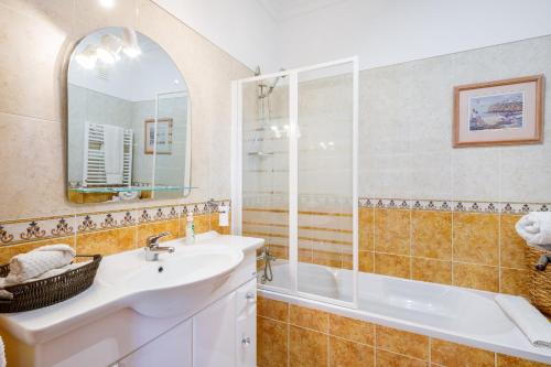 ein Badezimmer mit Waschbecken, Badewanne und Spiegel in der Unterkunft Colina Verde G - Charming 1-Bedroom Townhouse in Carvoeiro