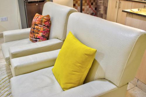 a white couch with a yellow pillow on it at Nimmoh's Homestays at Kishan Towers in Nanyuki