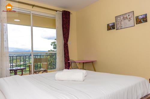 a bedroom with a bed and a large window at Nimmoh's Homestays at Kishan Towers in Nanyuki