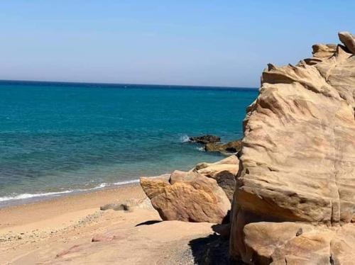 a beach with a large rock and the ocean at Miral Resort in Ain Sokhna