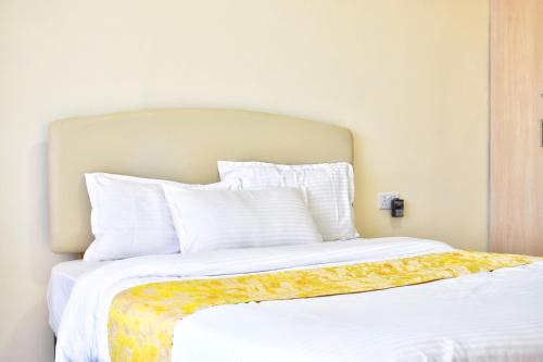 a large bed with white sheets and pillows at Nimmoh's Homestays at Kishan Towers in Nanyuki