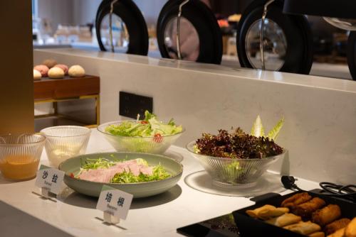 un mostrador con tres tazones de ensalada y otros alimentos en Atour X Hotel Guangzhou Avenue South Canton Fair-Free shuttle bus to Canton Fair, en Guangzhou