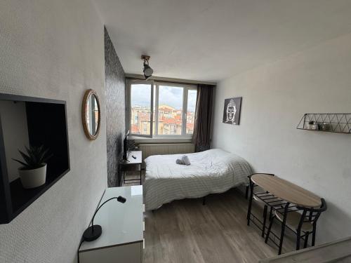 a bedroom with a bed and a table and a window at Studio au coeur de Valence 45 in Valence