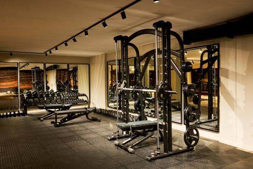 a fitness room with several tread machines and mirrors at Kruger Gate Hotel in Skukuza