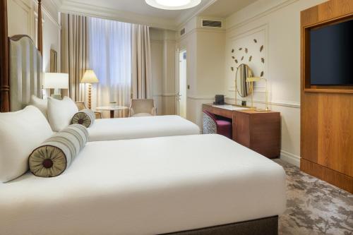 a hotel room with two beds and a flat screen tv at The Caledonian Edinburgh, Curio Collection by Hilton in Edinburgh