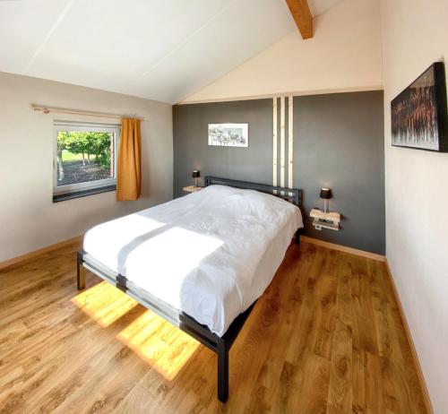 a bedroom with a large bed and a wooden floor at Welcoming house in Stavelot with sauna and garden in Francheville