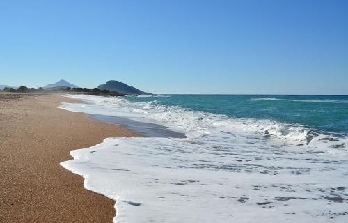 a sandy beach with waves on the ocean at Gialova SUNSET VILLA with Seaview & Private Pool in Gialova