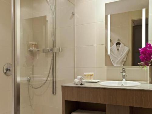 a bathroom with a sink and a shower with a mirror at Pullman Bordeaux Lac in Bordeaux