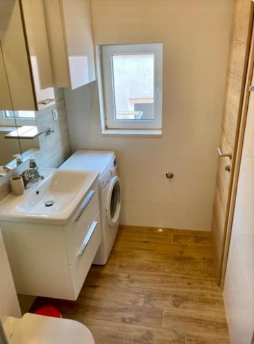 a bathroom with a sink and a washing machine at Apartments SKY in Brela