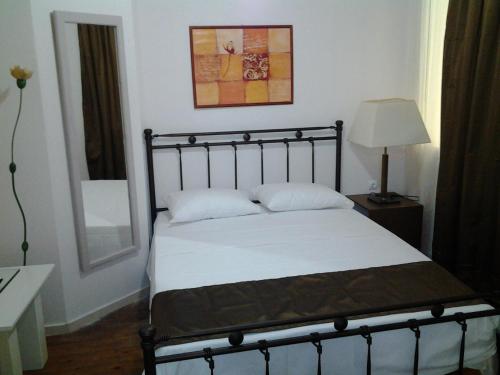 une chambre avec un lit avec des draps blancs et une lampe dans l'établissement Mastic Point Studios, à Chios