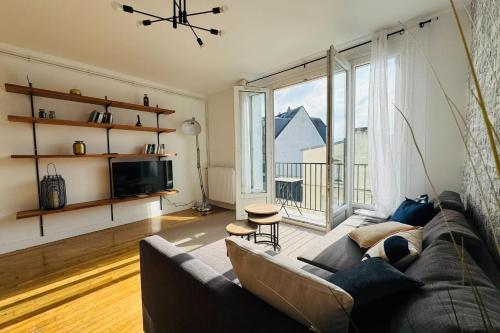 un salon avec un canapé et une grande fenêtre dans l'établissement 5-room apartment in the heart of the city center, à Caen