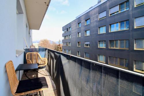 a balcony with two chairs and a table and a building at Graz central Penthouse Style Apt in Graz