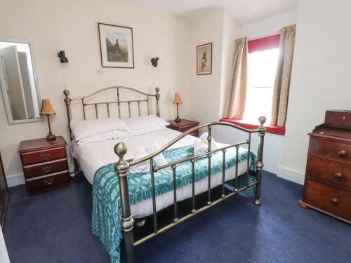 a bedroom with a bed and a dresser at Brackenbury Cottage in Caernarfon