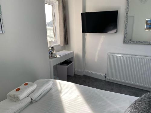 a white bedroom with a bed and a tv on the wall at Marine View Guest House in Scarborough