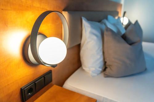a lamp on the wall next to a bed with pillows at Mercure Salzburg City in Salzburg