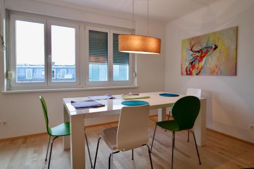 a dining room with a white table and green chairs at Graz central Penthouse Style Apt in Graz