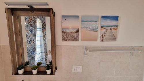 ein Badezimmer mit Spiegel und Bildern an der Wand in der Unterkunft Casa Emma in San Nicola Arcella