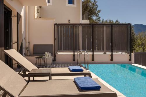 a swimming pool with two lounge chairs next to a house at Villa Theoni in Asos
