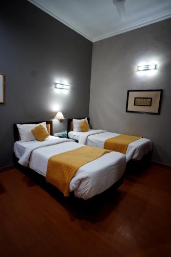 a hotel room with two beds with yellow blankets at The Corus Hotel in New Delhi
