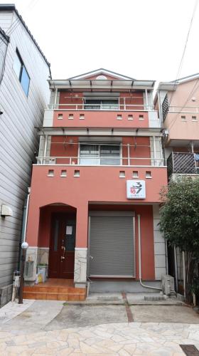 a red building with a garage in front of it at 駅徒歩1分 観光拠点に最適なゆったり快適一軒家 in Osaka