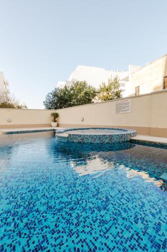 a swimming pool with blue water in a building at Family duplex apartment w shared pool by Homely in Mellieħa