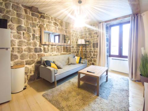 un salon avec un canapé et un mur en pierre dans l'établissement Appartement 35m2, à Montpezat-sous-Bauzon