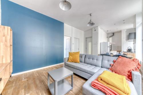 - un salon avec un canapé gris et un mur bleu dans l'établissement Appartement Antonin - Welkeys, à Villeurbanne