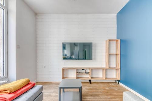 un salon avec un canapé et une télévision sur un mur dans l'établissement Appartement Antonin - Welkeys, à Villeurbanne