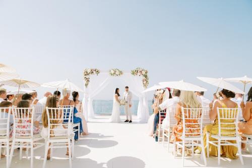 a bride and groom walking down the aisle at their wedding ceremony at Grecotel LUXME White in Adelianos Kampos