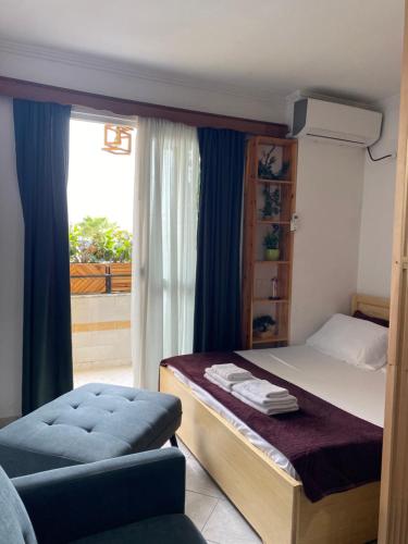 a bedroom with a bed and a chair and a window at Studioo Apartment in Tirana