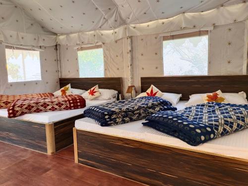a bedroom with three beds in a tent at Shakoon Camps & Farmstay Nainital in Nainital