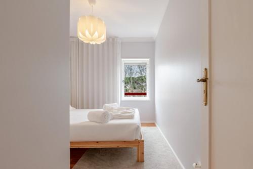 a white bedroom with a bed and a window at Seaside Urban Retreat – 5min to Esposende Beach in Esposende