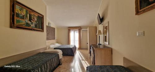 a hotel room with two beds and a desk at Hotel Chopin in Fiumicino