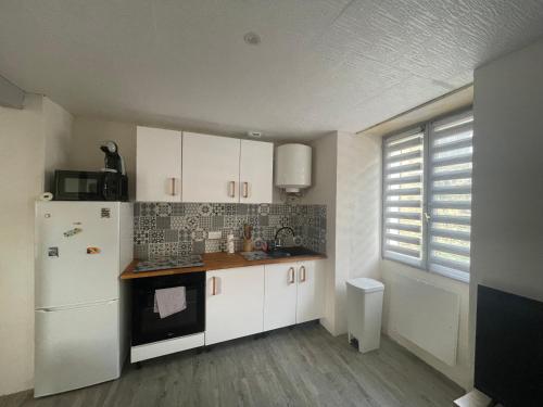 une cuisine avec des armoires blanches et un réfrigérateur blanc dans l'établissement Petite maison de ville, à Sainte-Maure-de-Touraine